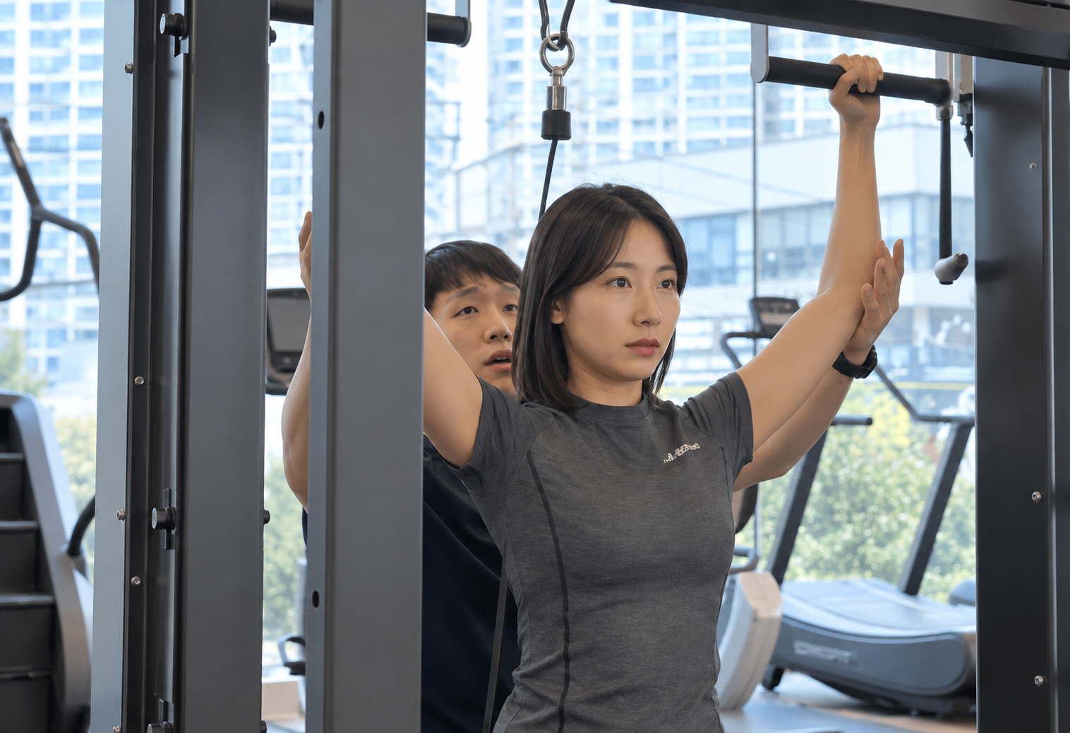 현대식 운동 공간에서 트레이너와 풀다운 운동을 하는 여성